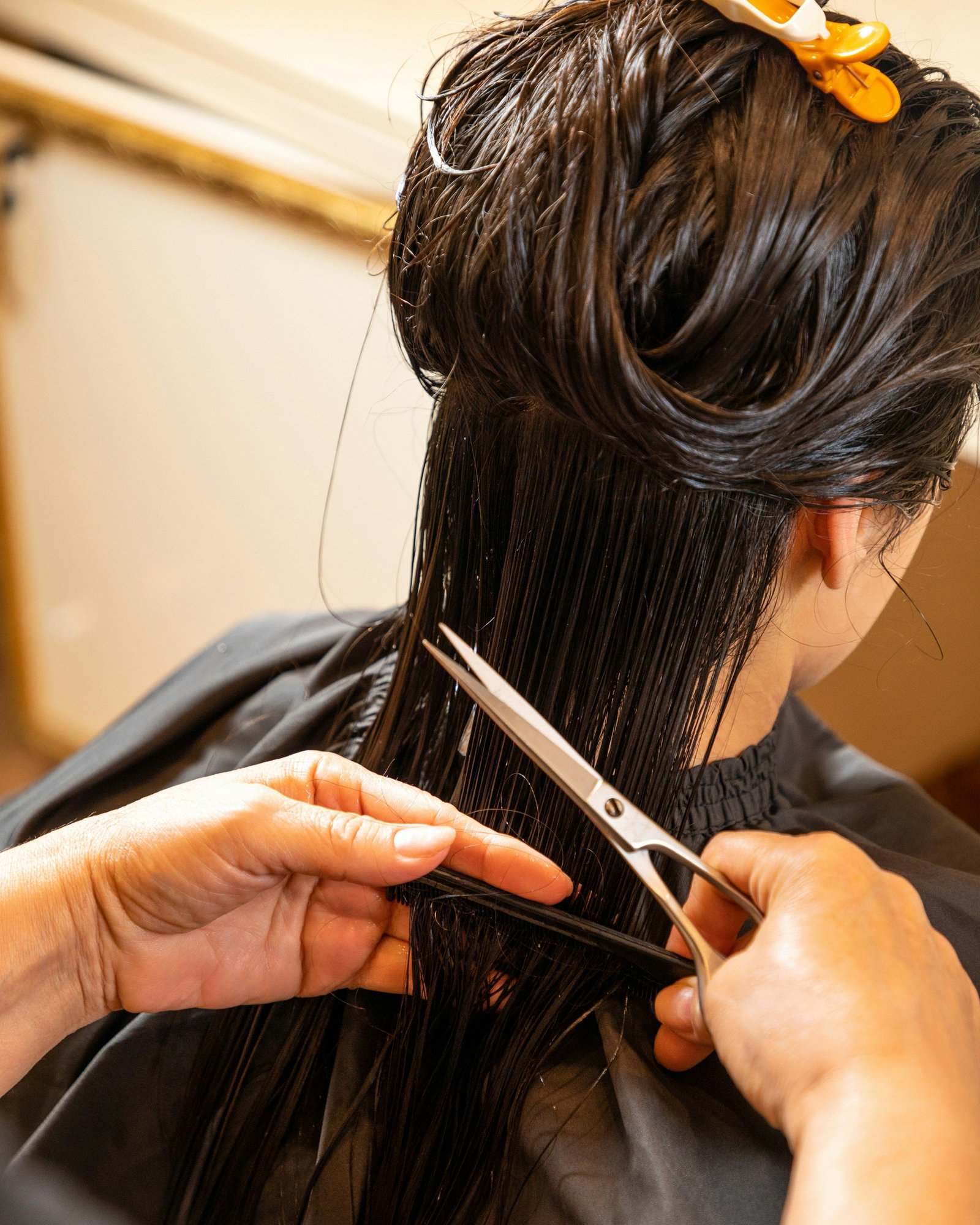 Stylist cutting long dark hair with scissors